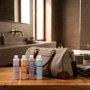 photo professionnelle lifestyle, ensemble de 4 produits capillaires beauté insolente présentés sur un meuble a côté d'un sac de sport. 4 flacons de taille small 100ml pour cheveux bouclés.